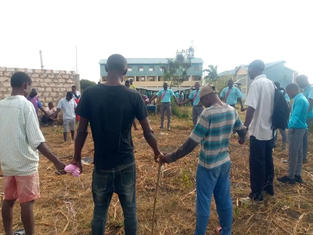 A group of people standing around in the grass.