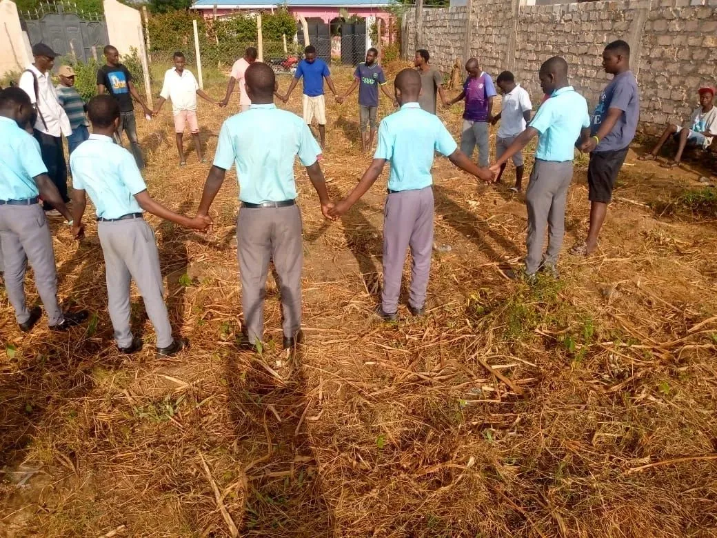 A group of people standing in the grass holding hands.