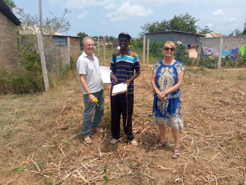 Three people standing in a field with one holding a piece of paper.