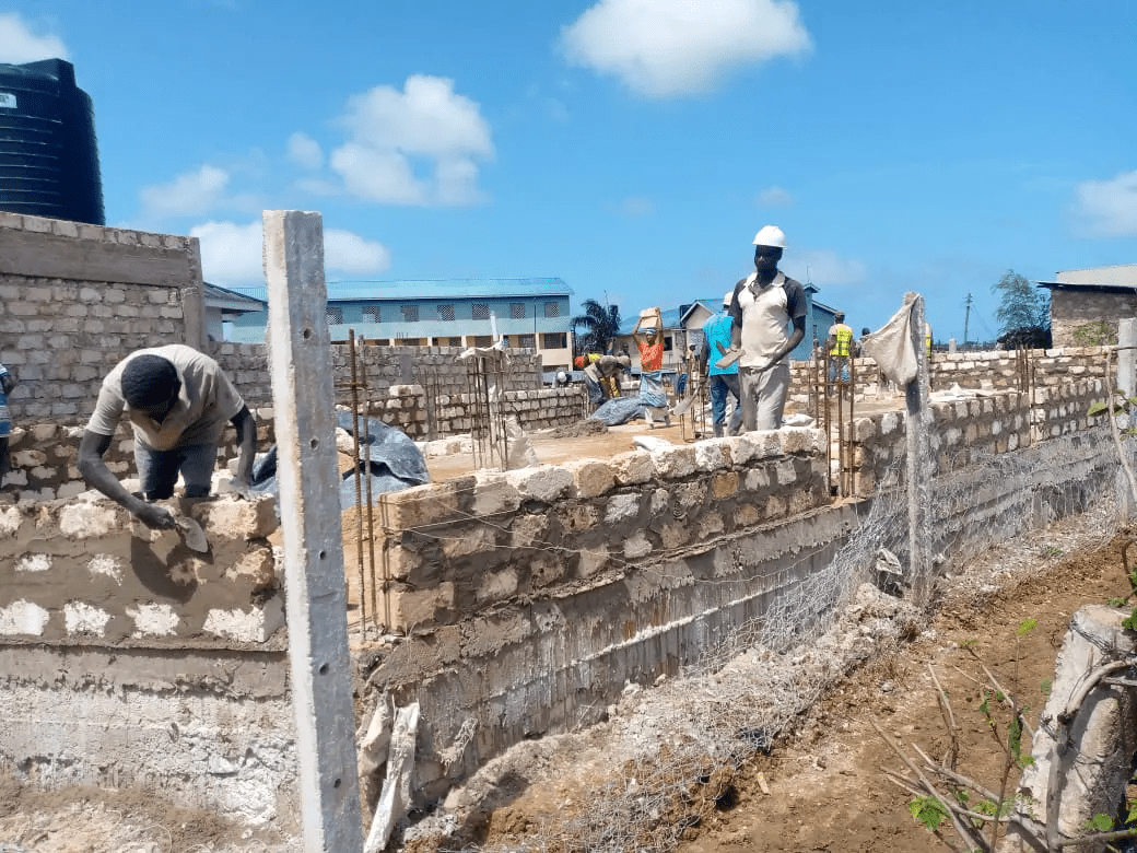 A group of people building a wall with bricks.