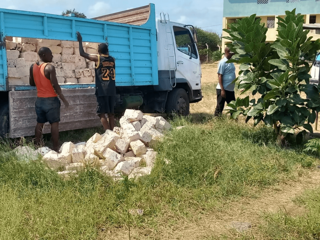 A truck with boxes of wood is parked in the grass.