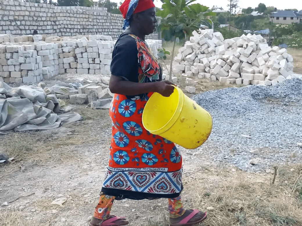 A woman carrying a yellow bucket in her hand.