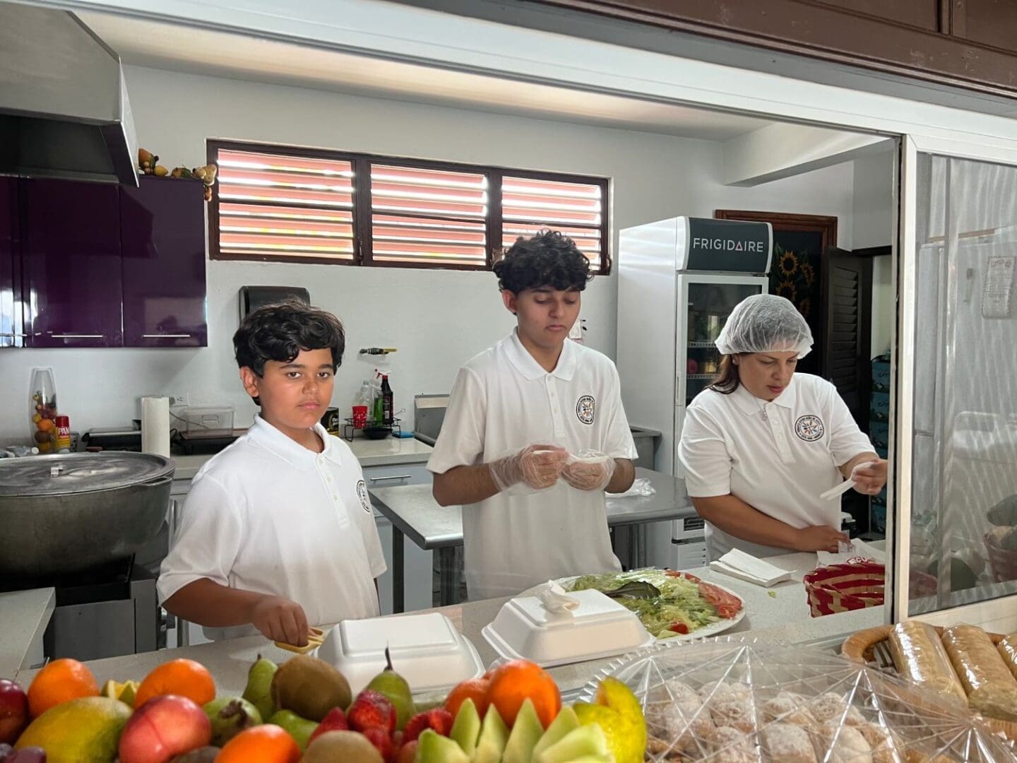 Three people in a kitchen preparing food.